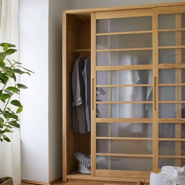 a wooden closet with glass doors next to a potted plant