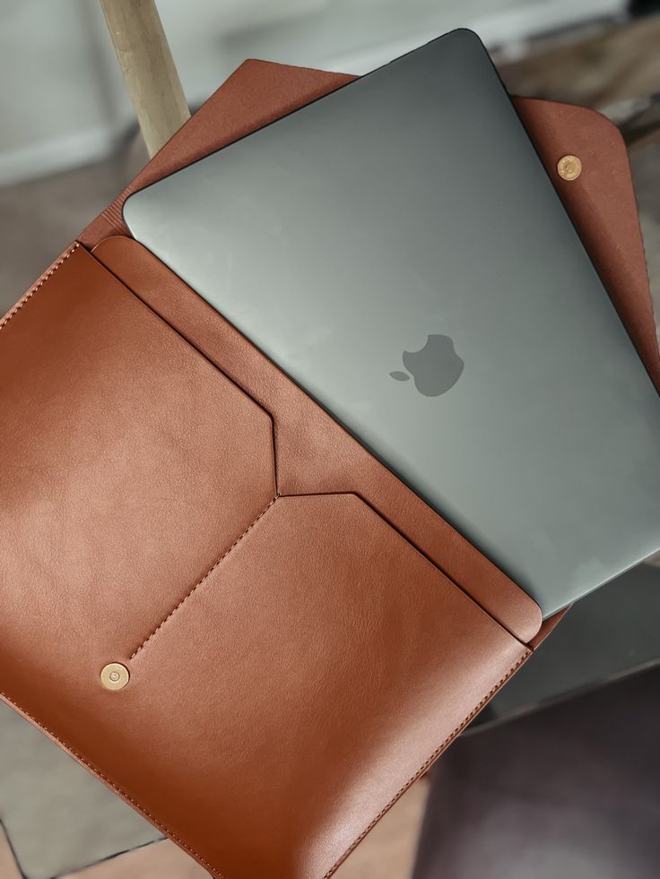 two laptops sitting on top of each other in leather cases, one is open and the other is closed