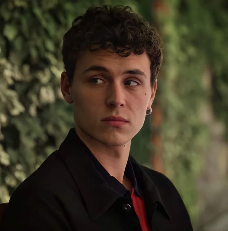 a young man in a black shirt and red tie looking at the camera with an intense look on his face