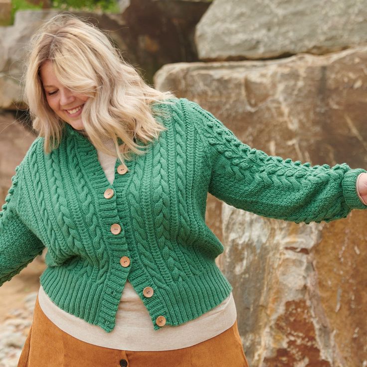 a woman in a green cardigan and tan skirt holding her hands out to the side