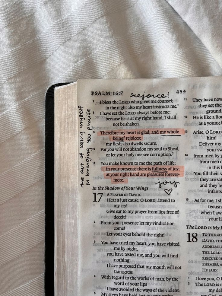 an open bible laying on top of a white sheet covered in text and writing from the book