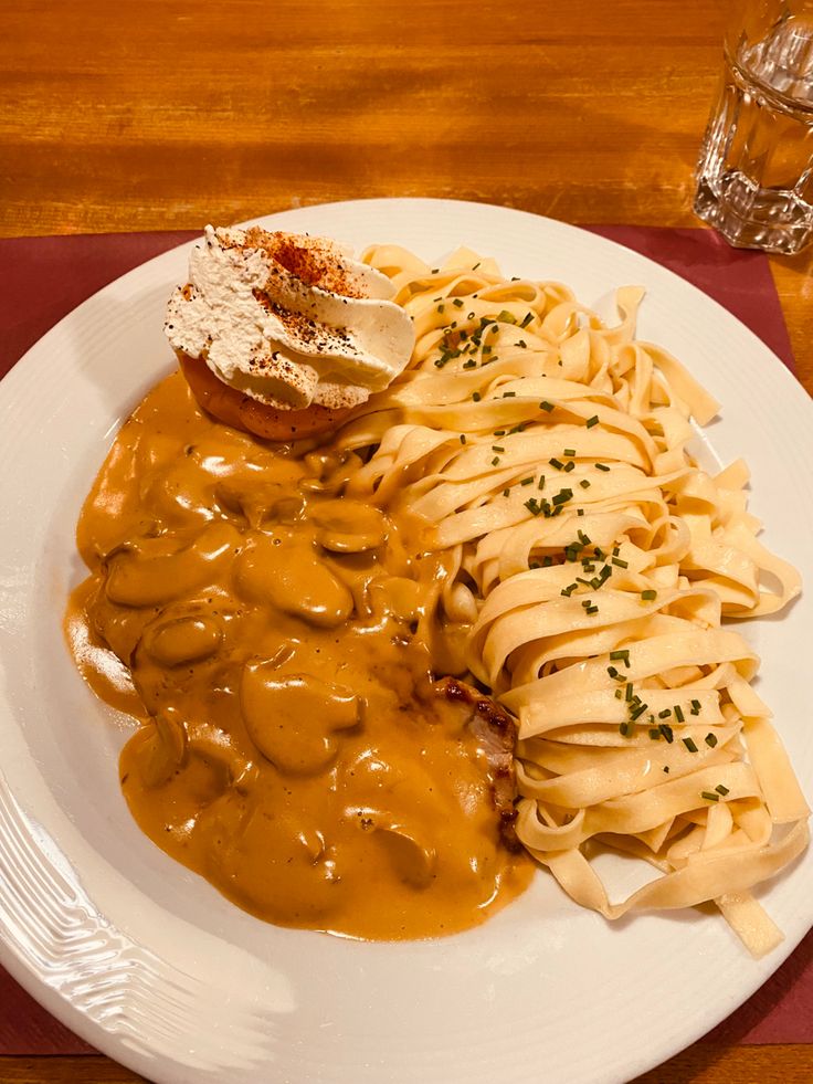 a white plate topped with pasta covered in gravy