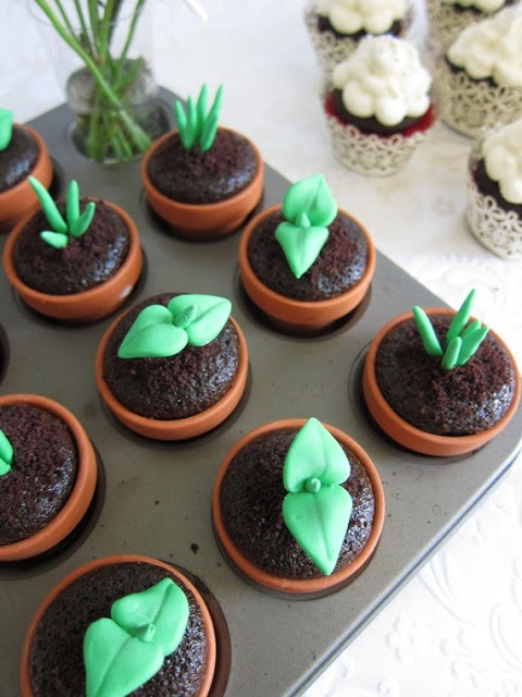 cupcakes decorated with green icing and sprouts are on a tray