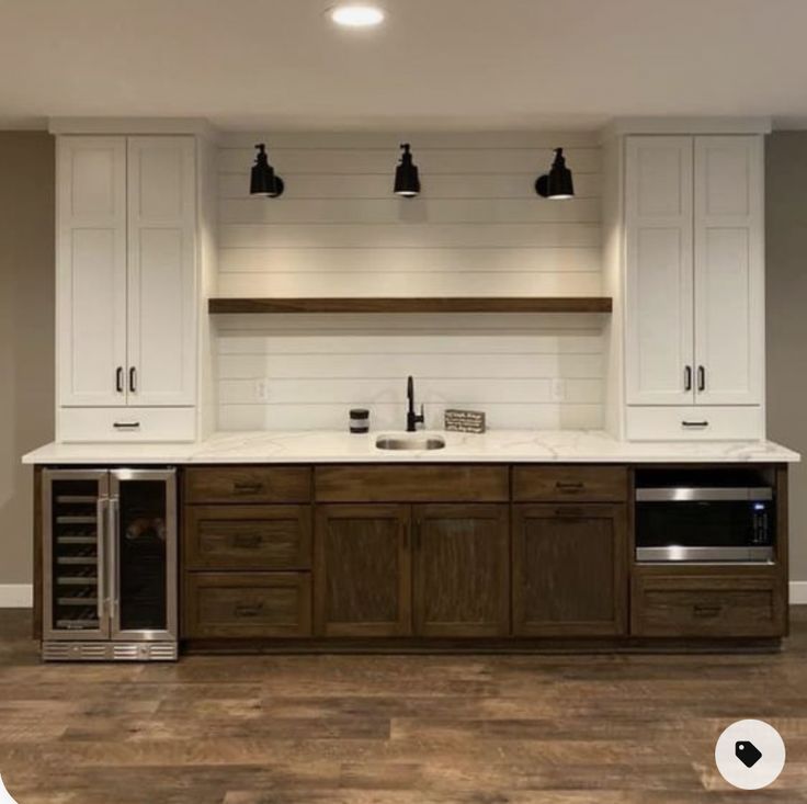 an empty kitchen with white cabinets and wood flooring is pictured in this image, there are three lights on the ceiling