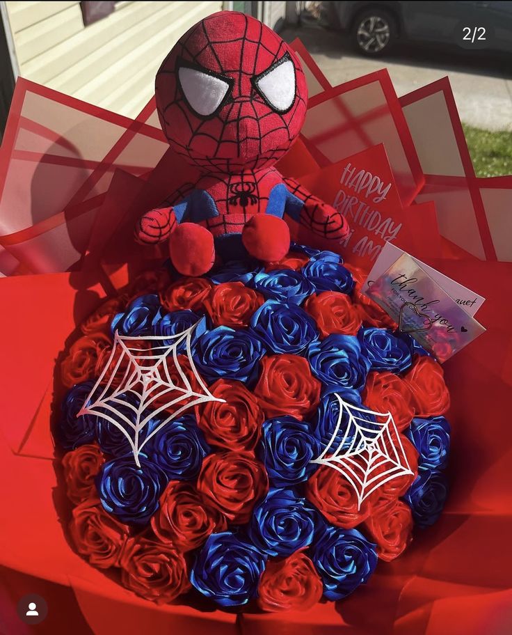 a spiderman cake with red, white and blue roses in it's center