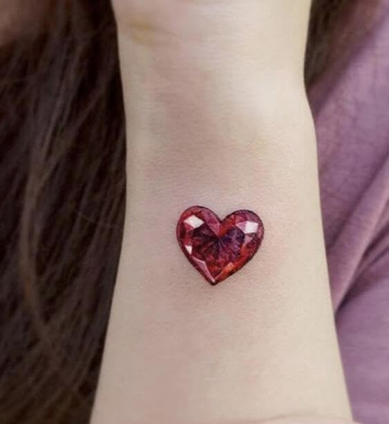 a woman with a red heart tattoo on her wrist