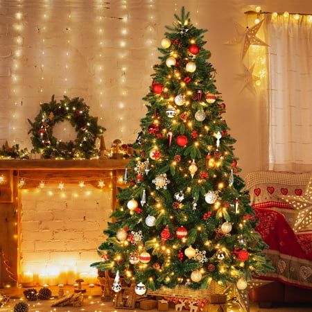 a decorated christmas tree sitting in front of a fire place with presents under the lights