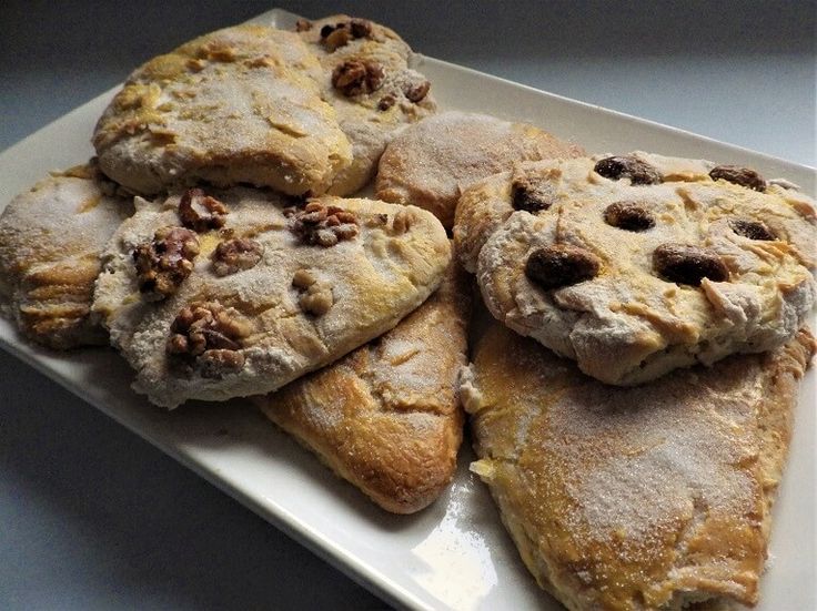 a white plate topped with cookies covered in powdered sugar and walnuts on top of it