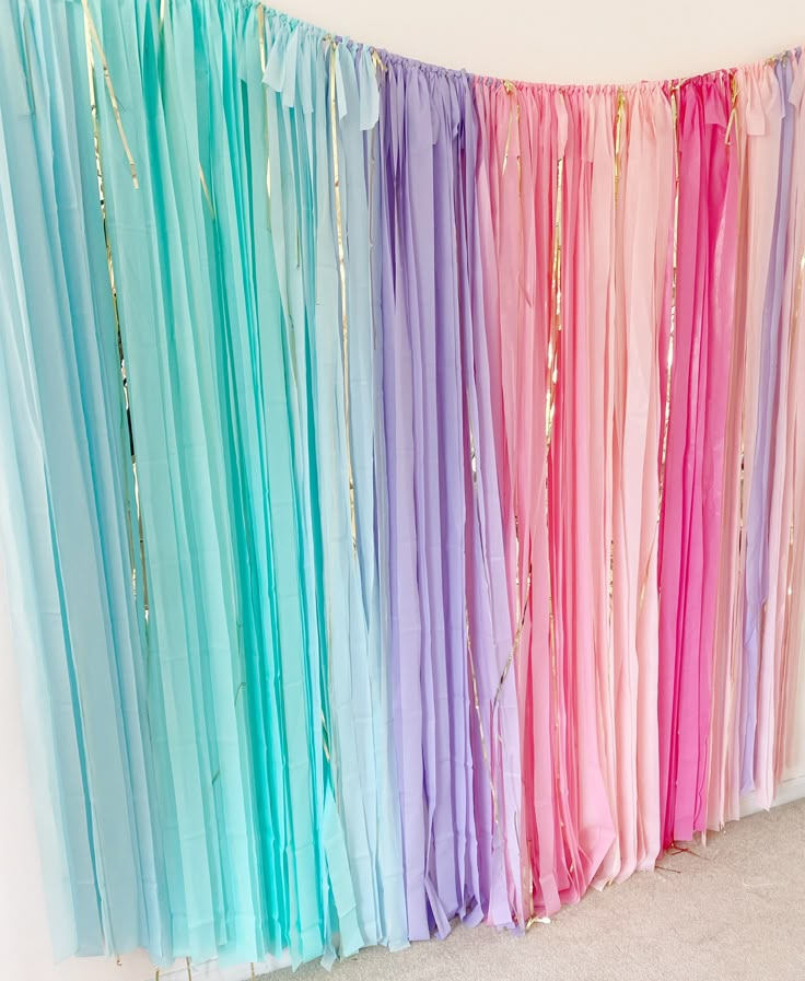 there are many different colored streamers hanging from the wall in front of a white wall