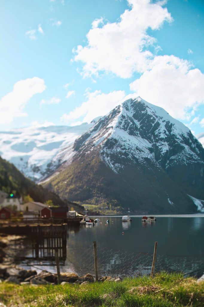 the mountains are covered in snow as boats sit on the water