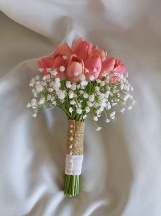 a bouquet of pink tulips and baby's breath on a white sheet