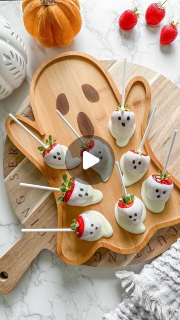 a wooden board topped with marshmallows and strawberries