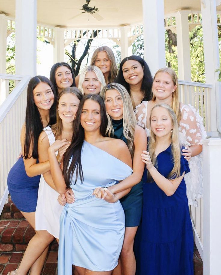 a group of women standing next to each other in front of a gazebo on a sunny day