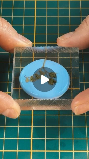 two hands holding a piece of plastic with wires in it on top of a table