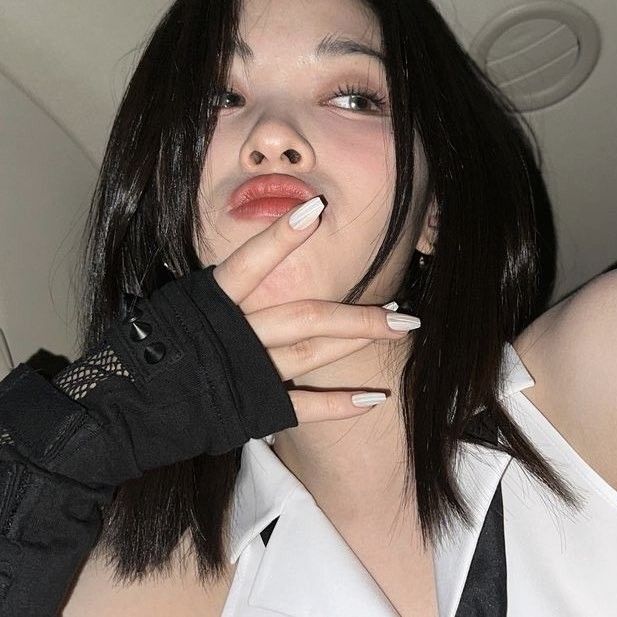 a woman with long black hair and white nails is holding her hand over her mouth