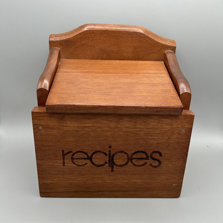 a small wooden box with the word recipes written in black on it, sitting on a white surface