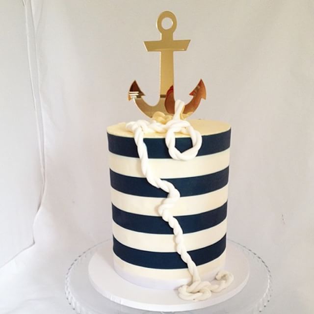 there is a blue and white striped cake with an anchor on the top that has rope around it