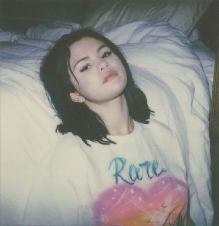 a woman laying on top of a bed in a white shirt