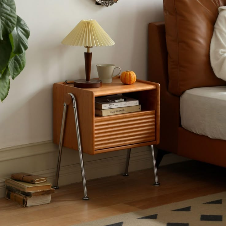 a nightstand with a lamp on it next to a bed