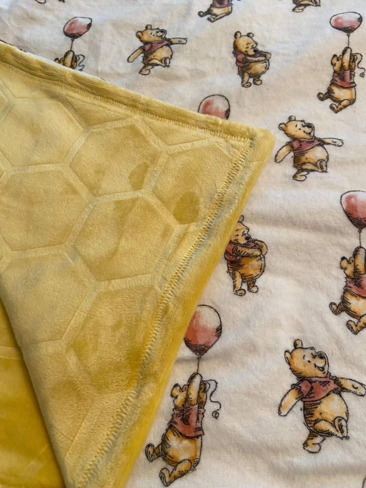 two sheets with winnie the pooh designs on them and one has a yellow blanket