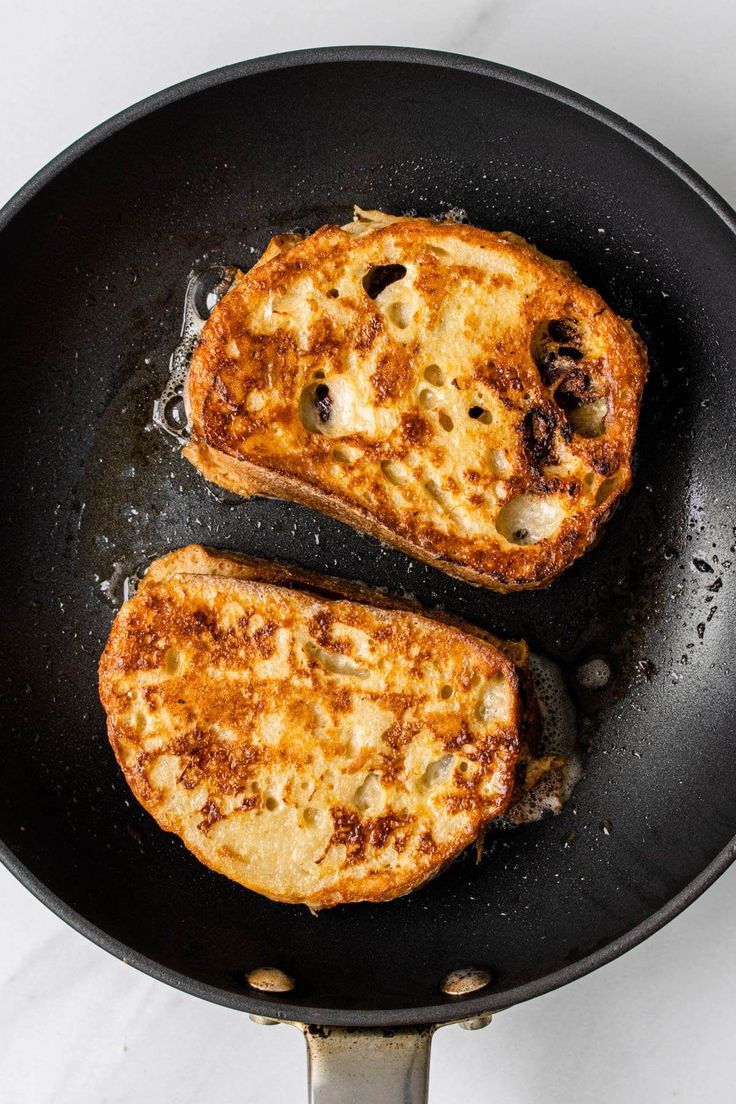 two pieces of bread are cooking in a frying pan on the stove top,