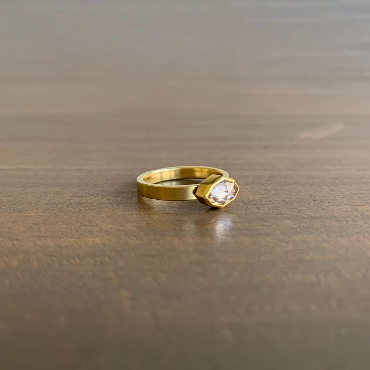 two gold rings sitting on top of a wooden table with a diamond in the middle