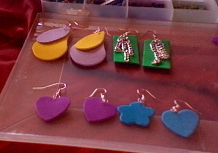 several pairs of heart shaped earrings are on display in a clear box with red sheets