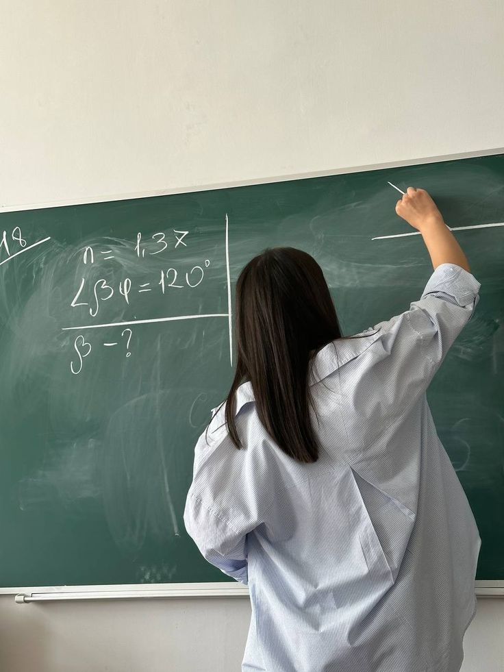 a woman writing on a blackboard with chalk