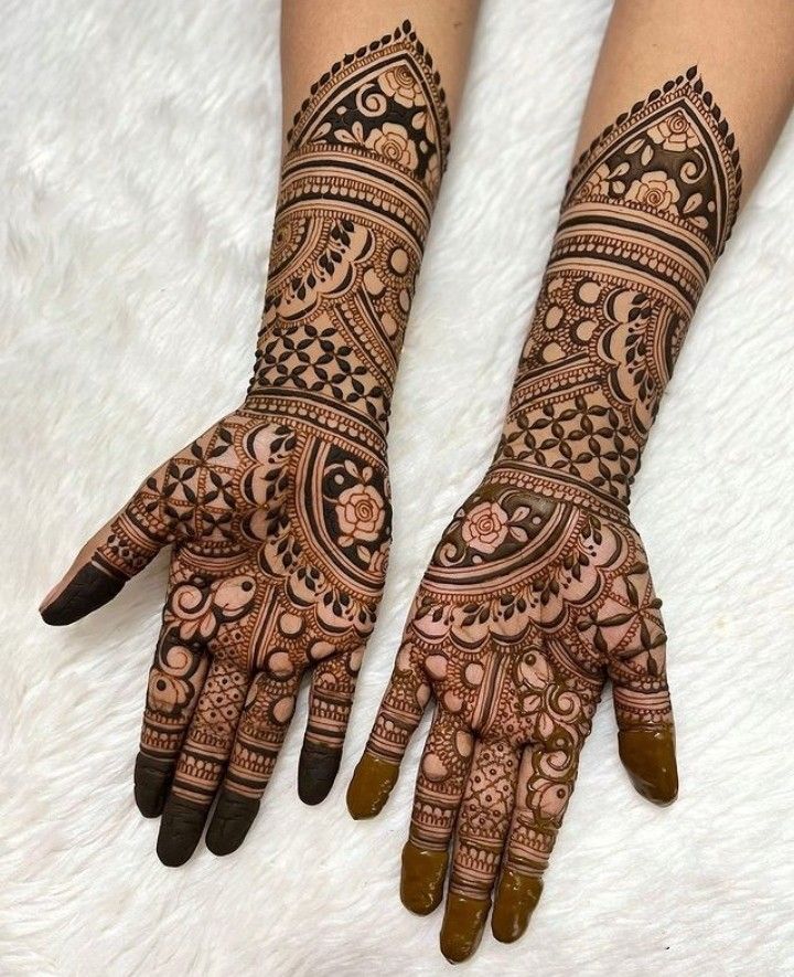 two hands with henna tattoos on them, one is showing the intricate design and the other has flowers