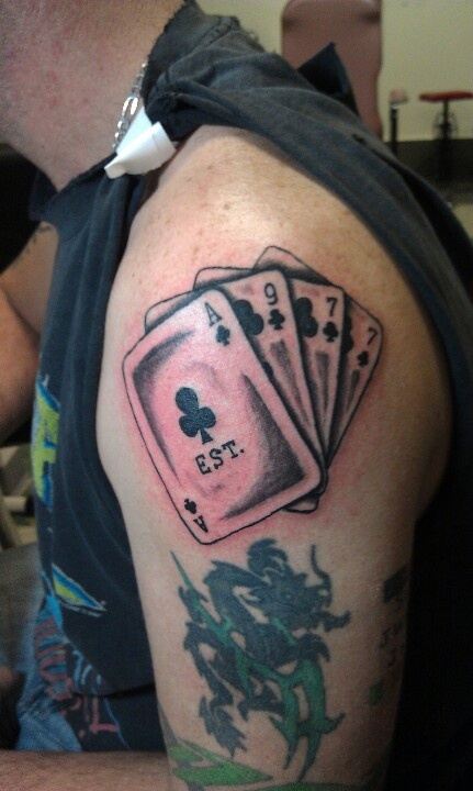 a man with a tattoo on his arm holding playing cards