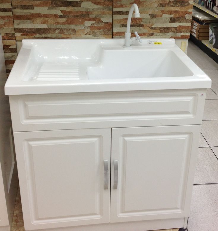 a white kitchen sink sitting on top of a counter next to a brick wall in a store