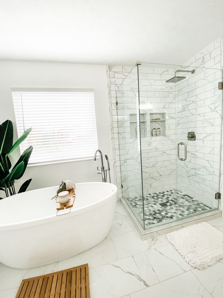 a bathroom with a large white bathtub next to a walk in shower