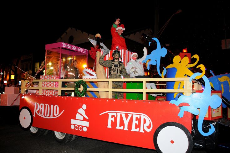 a man riding in the back of a red truck with decorations on it's side