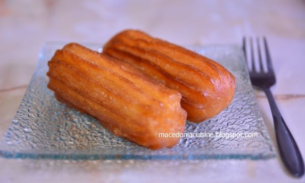 two glazed donuts on a glass plate next to a fork