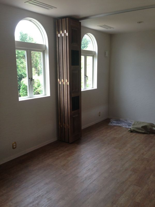 an empty room with wood floors and two windows