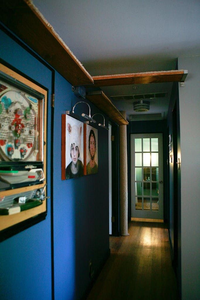 a hallway with blue walls and pictures hanging on the wall, along with wooden flooring