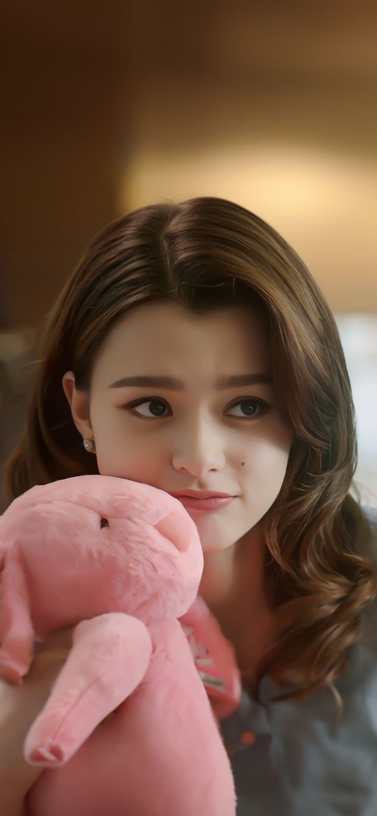 a girl holding a pink stuffed animal in her hands