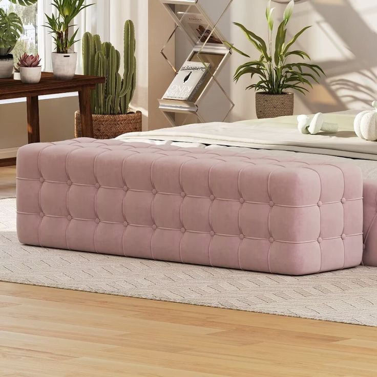 a bed with a pink tufted mattress on top of it next to potted plants