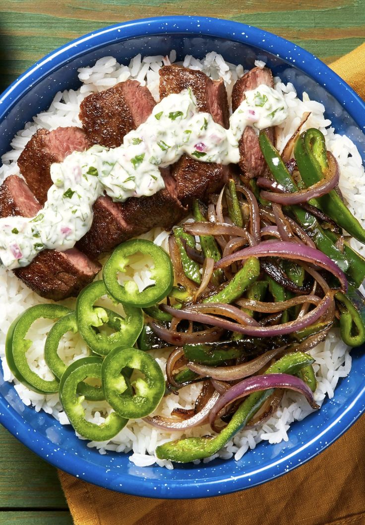 a blue bowl filled with rice, meat and veggies on top of it