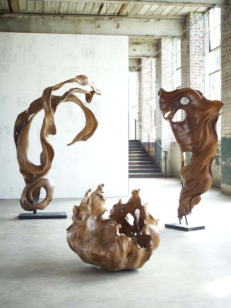 three wooden sculptures sitting in an empty room