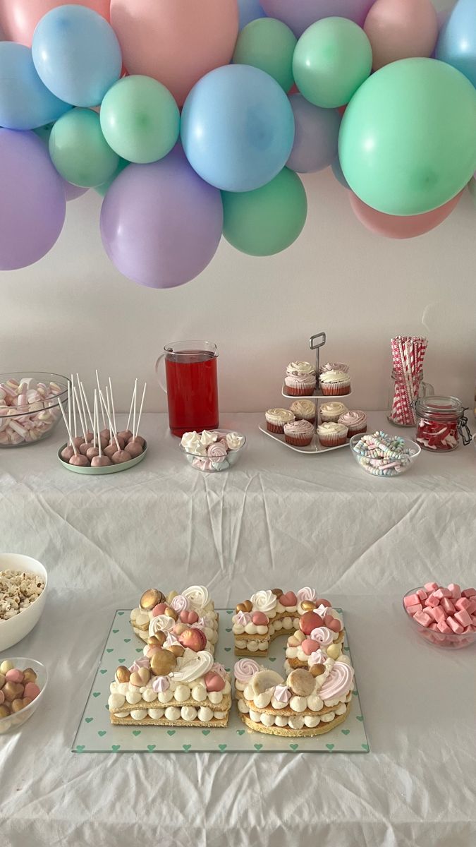 a table topped with lots of desserts and balloons