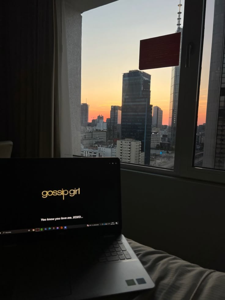 an open laptop computer sitting on top of a bed in front of a large window