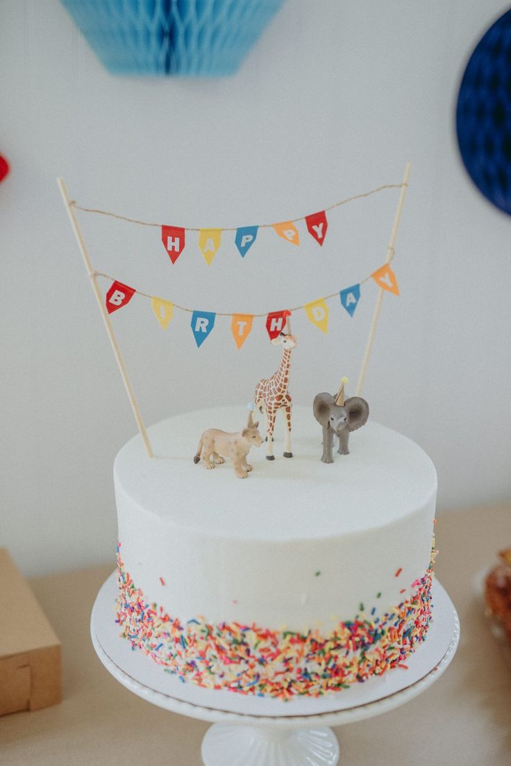 a birthday cake with two giraffe figurines on top and decorations around it