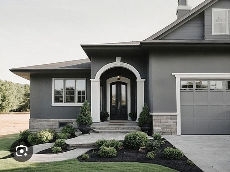 a gray house with white trim and two garages on the front door is shown