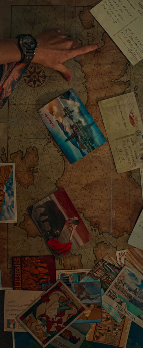 a person's hand on top of a map covered in postcards