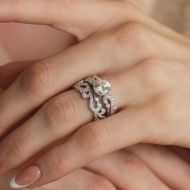 a woman's hand with a diamond ring on top of her finger and an engagement band