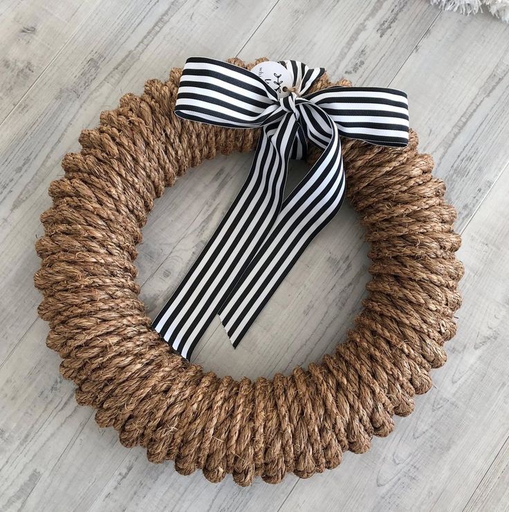 a black and white striped wreath with a bow on the front, sitting on a wood floor