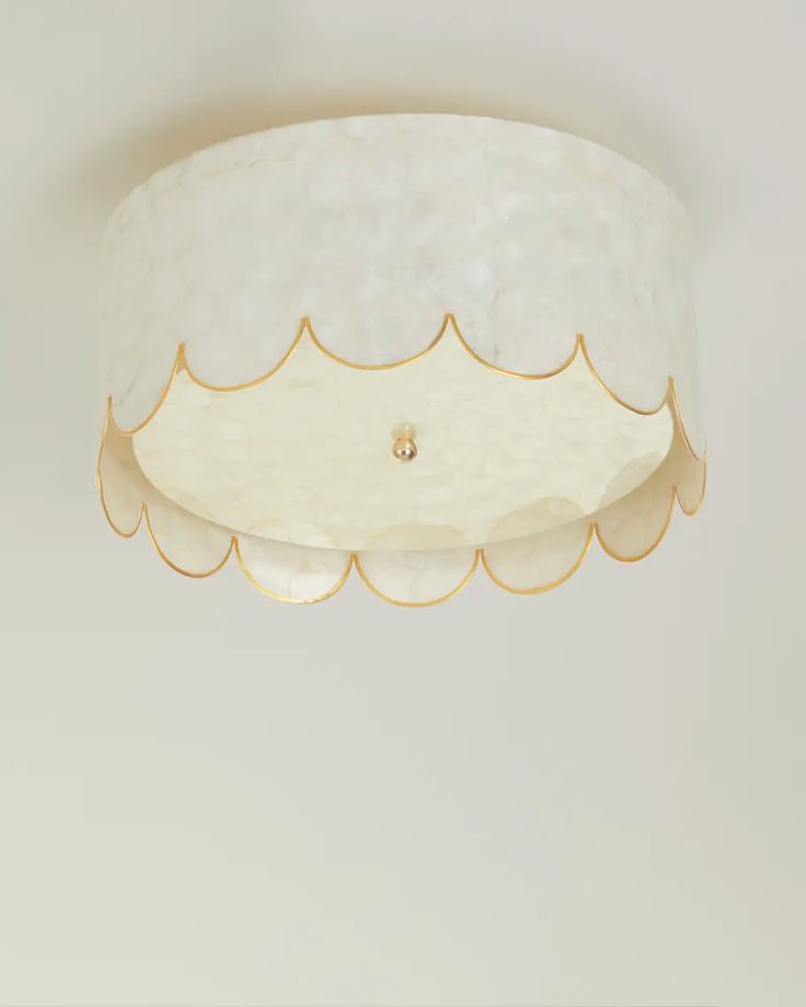 a white ceiling light with gold trim and scalloped glass shades on the bottom