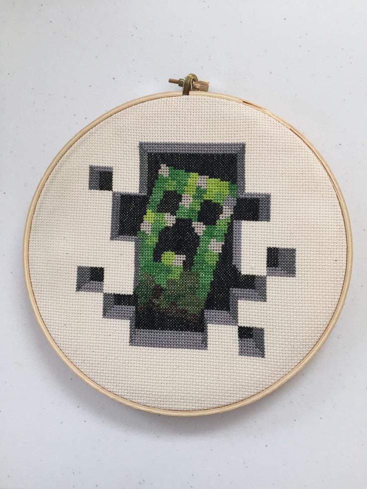 a cross - stitch pattern with an image of a green plant in the center on a white background