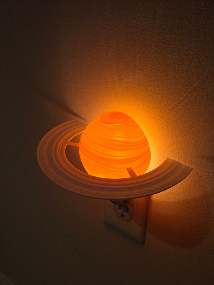 a light that is on the side of a wall with a saturn lamp attached to it